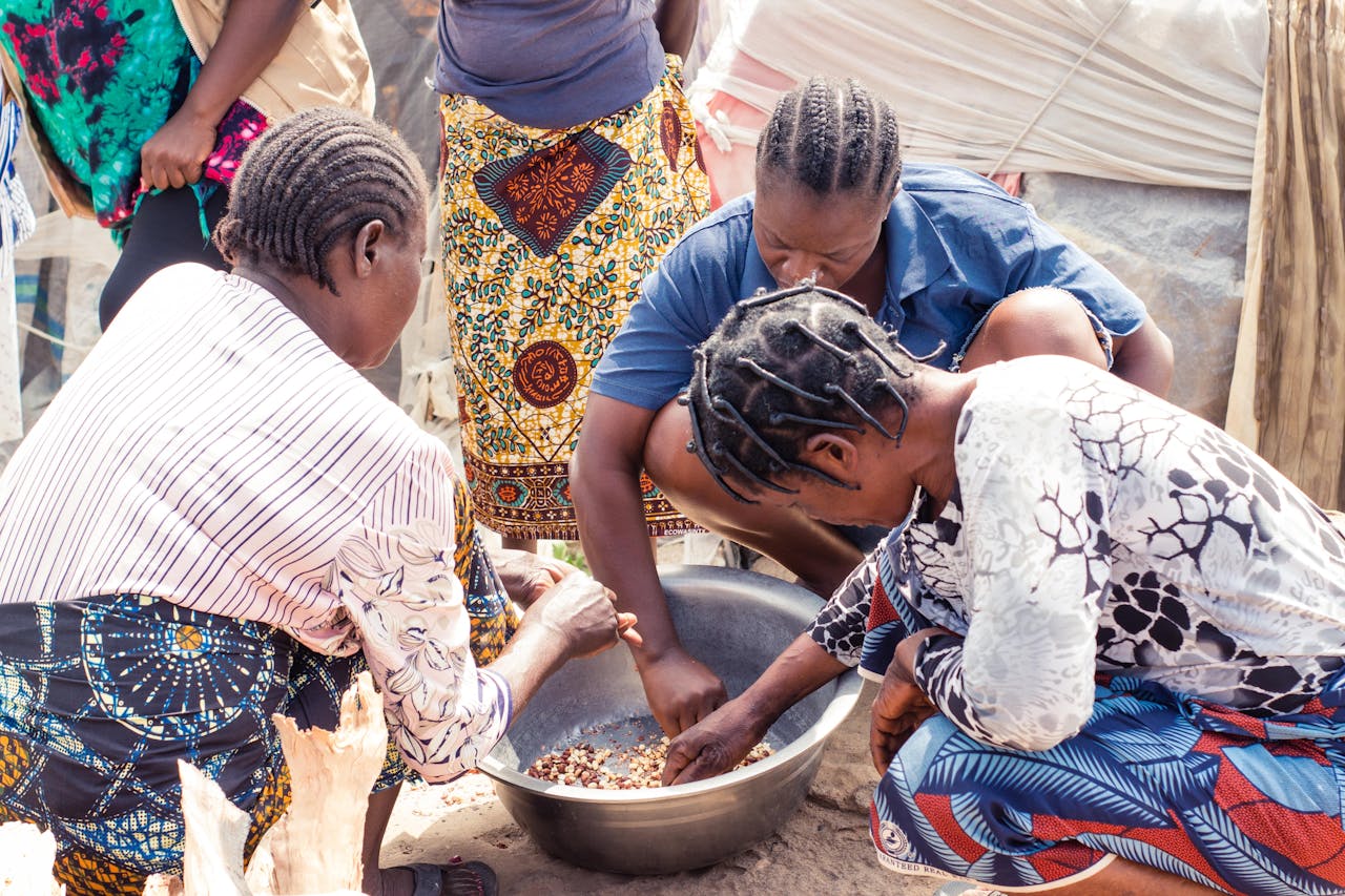services-01 Group of women collaboratively sorting beans outdoors, showcasing cultural richness.